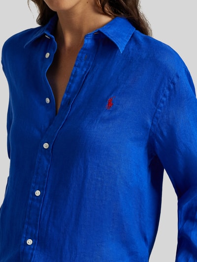 Kobiece modelka nosi Hemdbluse aus reinem Leinen von Polo Ralph Lauren, intensywnie niebieski kolor, luźny krój, detal z logo, zbliżenie na górną część ciała.