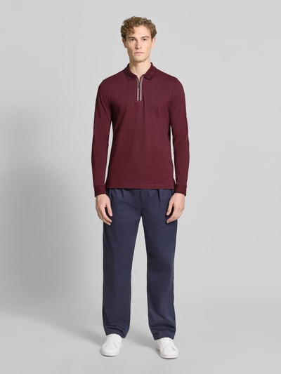 Männermodel trägt Slim Fit Poloshirt mit Reißverschluss von Christian Berg Men in Bordeaux, reine Baumwolle, Longsleeve, Ganzkörperansicht von vorne.