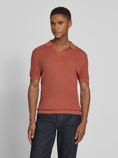 Männermodel trägt Slim Fit Strick-Poloshirt mit Strukturmuster Modell 'BRAIAN' von Drykorn in Rostrot aus reiner Baumwolle, Ganzkörperansicht von vorne.
