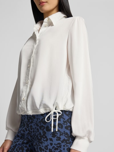 Frauenmodel trägt Regular Fit Bluse mit Tunnelzug von Marc Cain in Weiß, Knopfleiste, Hemdblusenkragen, glatter Stoff, Nahaufnahme Oberkörper.