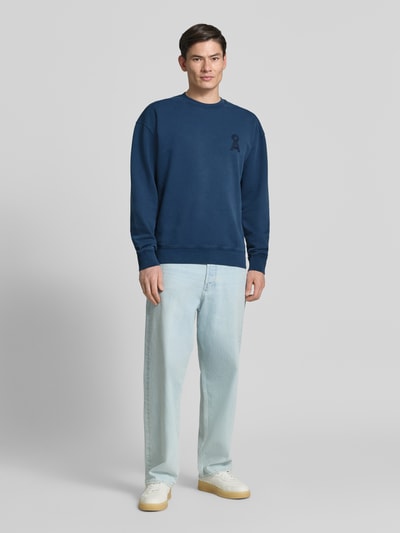 Männermodel trägt Relaxed Fit Sweatshirt aus reiner Bio-Baumwolle Modell 'ICONIC GMT DYE' von Armedangels in Dunkelblau, Ganzkörperansicht von vorne.