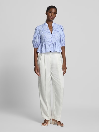 Frauenmodel trägt Regular Fit Bluse mit Stitchings Modell 'CAPUCHIN' von MANGO aus reiner Baumwolle in Hellblau mit V-Ausschnitt, Knopfleiste und 3/4-Arm, lockere Form, florale Textur, kombiniert mit heller Hose, Ganzkörperansicht von vorne.