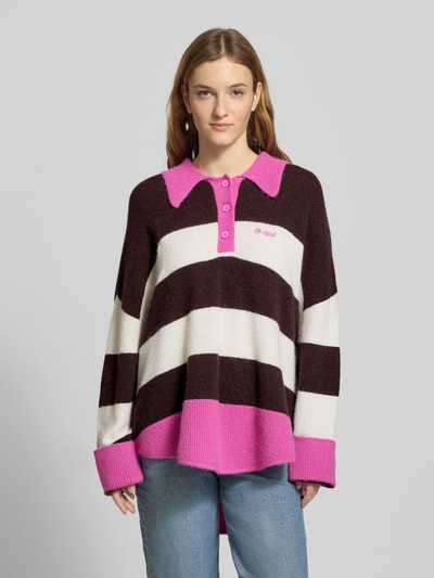 Frauenmodel trägt Oversized Strickpullover mit Polokragen Modell 'Maya' von OH APRIL, Blockstreifen braun, weiß, pink, lockere Passform, gerippte Abschlüsse, Label-Stitching, Material-Mix mit Woll-Anteil, Ganzkörperansicht von vorne.