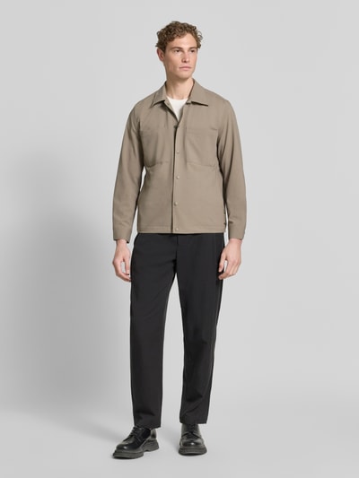 Männermodel trägt Regular Fit Overshirt mit Baumwoll-Anteil - Marc O'Polo × DFB Travel Collection in Beige und Schwarz, Ganzkörperansicht von vorne
