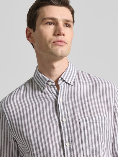 Männermodel trägt Modern Fit Freizeithemd aus reinen Leinen Modell 'Daniel' von Brax, grau-weiß gestreift, Button-Down-Kragen, Nahaufnahme Oberkörper.