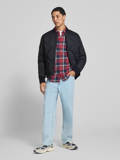 Männermodel draagt Regular Fit Steppjacke mit Stehkragen van Superdry in zwarte Stiksels look, Steekzakken, ritssluiting, regular fit, elastische mouwboorden, Ruglengte maat M 69cm, schouderbreedte 46cm, borstwijdte 58cm, mouwlengte 59cm, Ganzkörperansicht van voren.