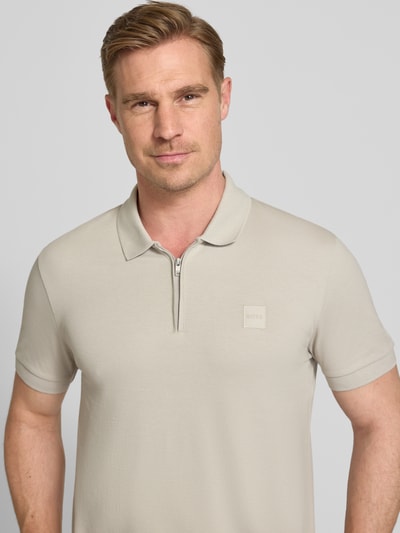 Männermodel trägt Slim Fit Poloshirt aus Baumwoll-Mix Modell 'PASSERZIP' von BOSS Orange, Optik: Unifarben, Nahaufnahme Oberkörper.