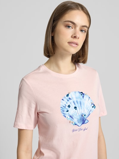 Frauenmodel trägt Regular Fit T-Shirt aus reiner Baumwolle Modell 'KITA' von Only in Hellrosa mit Muschel-Motiv, Pailletten, Perlen und Glitzer-Print, aus Jersey, Nahaufnahme Oberkörper.