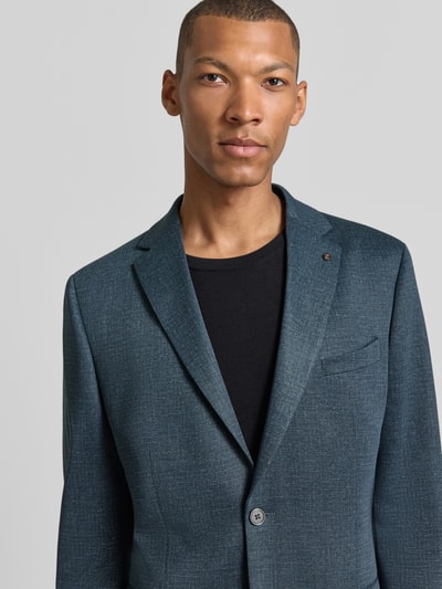 Männermodel trägt Slim Fit Sakko mit Lyocell-Anteil Modell 'Nick' von Zuitable, strukturierte blaue Oberfläche, Nahaufnahme Oberkörper.