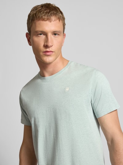 Männermodel trägt Regular Fit T-Shirt aus reiner Baumwolle von G-Star in Melange-Optik mit Label-Patch, Jersey-Material, Nahaufnahme Oberkörper.