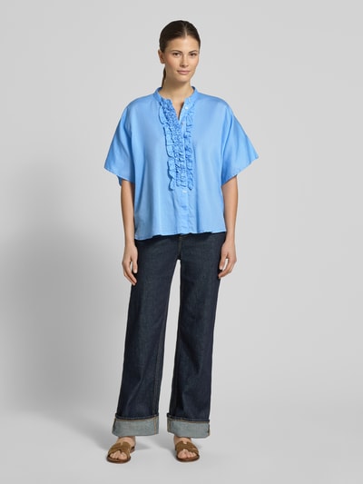 Frauenmodel trägt Relaxed Fit Bluse mit Rüschen Modell 'DAISY' von 0039 Italy in Hellblau, reine Baumwolle, Ganzkörperansicht von vorne.
