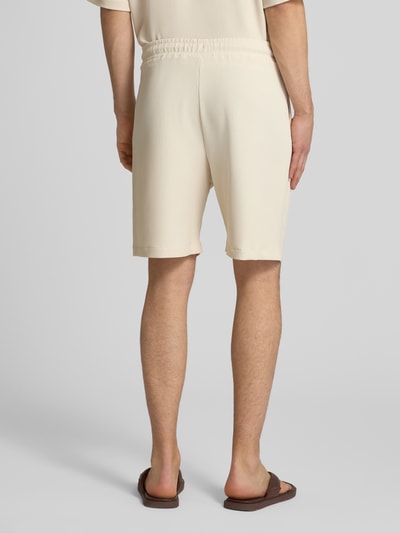 Männermodel trägt Shorts in Plissee-Optik mit elastischem Bund von REVIEW, Beige, Material-Mix mit Stretch-Anteil, Regular-Fit, Ganzkörperansicht Rückansicht.