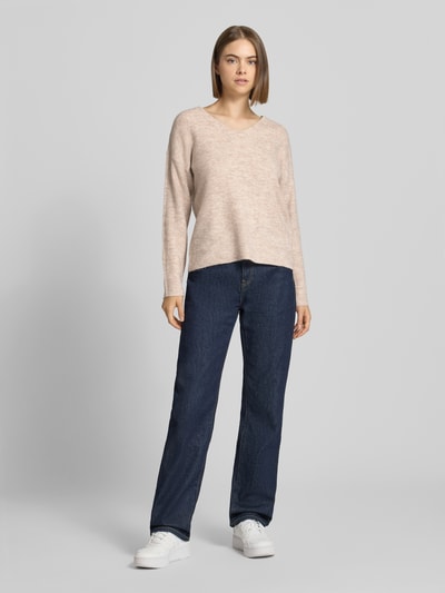 Frauenmodel trägt Regular Fit Pullover mit V-Ausschnitt Modell 'CAMILLA' von ONLY in Beige, kombiniert mit blauer Jeans, Ganzkörperansicht von vorne, Damen Pullover von ONLY