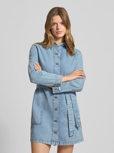 Frauenmodel trägt Minikleid in Denim-Optik mit Umlegekragen von Calvin Klein Jeans in Hellblau, reine Baumwolle, Taillierte Passform, Langarm, Knopfleiste, aufgesetzte Taschen, abnehmbares Taillenband, Nahaufnahme Oberkörper.
