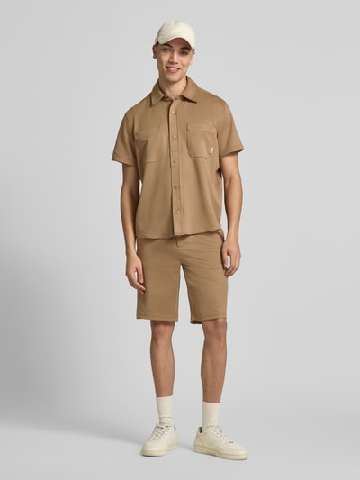 Männermodel trägt Regular Fit Bermudas Modell 'ADRIAN' von Blend in Beige, Material-Mix mit Viskose-Anteil, Eingrifftaschen, Ganzkörperansicht von vorne. Bundweite bei Größe M: 41 cm, Innenbeinlänge bei Größe M: 26 cm.