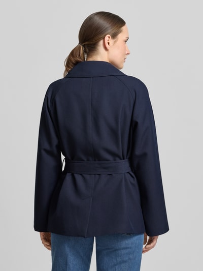 Vrouwenmodel draagt Jacke mit Reverskragen und Bindegürtel van Gant in donkerblauw materiaalmix met viscose, regular fit, met dubbele rij knopen, reverskraag, strikceintuur, ruglengte maat S 68 cm, schouderbreedte 40 cm, borstwijdte 53 cm, mouwlengte 58 cm. Ganzkörperaanzicht achteraan.