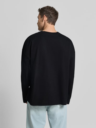 Männermodel trägt Longsleeve mit Logo-Print Modell 'GIXY' von American Vintage in Schwarz, reine Baumwolle, Rückenansicht, Ganzkörperansicht Rückansicht.