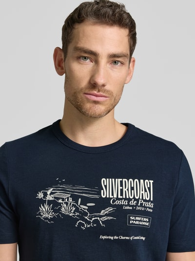 Męski model nosi Regular Fit T-Shirt aus reiner Baumwolle von s.Oliver RED LABEL, efekt: jednolity kolor, krój regular fit, nadruk z motywem, rękaw: krótki rękaw, bawełna, nahaufnahme oberkörper.