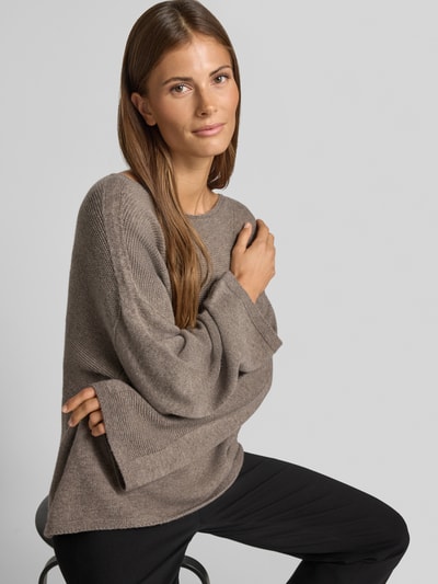 Frauenmodel trägt Oversized Pullover aus reiner Baumwolle in Strick-Optik von Emporio Armani, braun-graue Farbe, elastische Abschlüsse, Nahaufnahme Oberkörper.