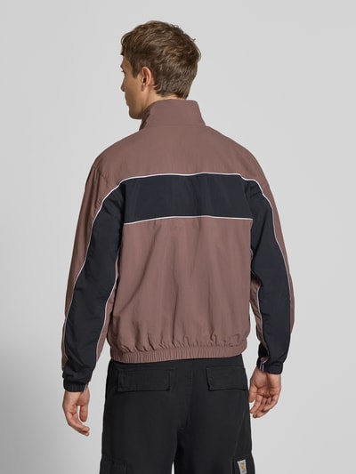 Männermodel trägt Regular-Fit Trainingsjacke mit Logo von Nike in Braun und Schwarz, Stehkragen, Rückenansicht, Ganzkörperansicht Rückansicht.