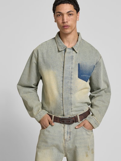 Männermodel trägt Ledergürtel aus echtem Leder von Diesel, braun, matte Textur, Pinschließe, Logo, dezenter Used-Look, Nahaufnahme Oberkörper.