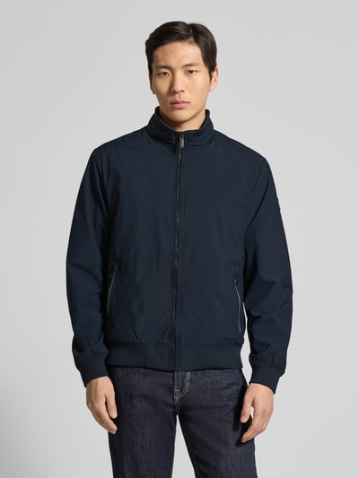 Männermodel trägt Regular Fit Jacke mit Stehkragen von Lerros in Dunkelblau, sichtbarer Reißverschluss, Eingrifftaschen, Ganzkörperansicht von vorne. Elastischer Material-Mix, Logo-Detail, elastische Abschlüsse, Maße für Größe M laut Beschreibung.