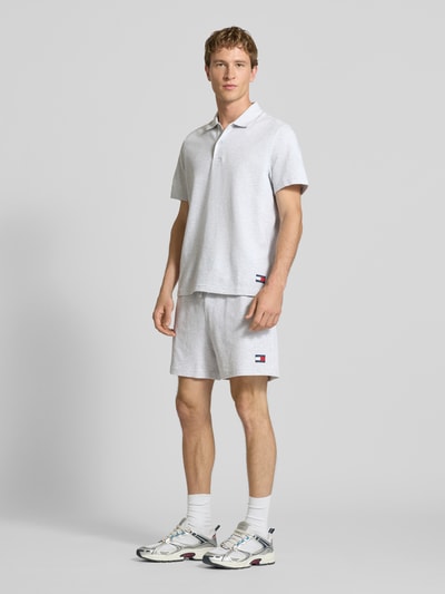 Männermodel trägt Regular Fit Poloshirt aus reiner Baumwolle von Tommy Jeans, Optik: Unifarben, Jersey, Logo-Stitching, Ganzkörperansicht von vorne.