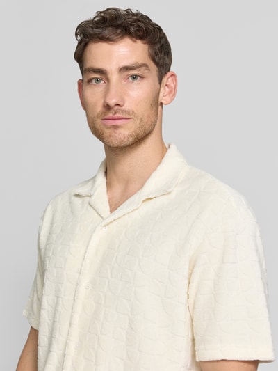 Männermodel trägt Regular Fit Freizeithemd mit Strukturmuster von MCNEAL in Creme mit Reverskragen, Nahaufnahme Oberkörper. Baumwoll-Mix, sichtbare Knopfleiste, feine Struktur.