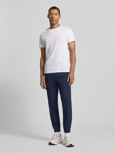 Männermodel trägt Slim Fit Jogger mit elastischem Bund von Fabletics, Dunkelblau, Elastischer-Material-Mix, Eingrifftaschen, Ganzkörperansicht von vorne.