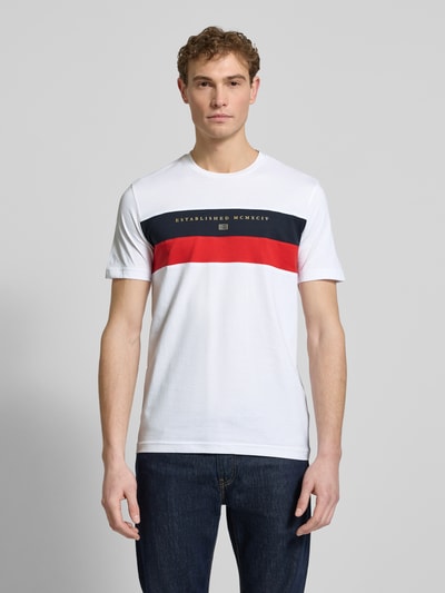 Männermodel trägt Regular Fit T-Shirt mit Rundhalsausschnitt von Christian Berg Men in Weiß mit Statement-Print, Ganzkörperansicht von vorne.
