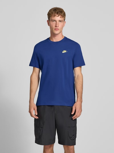 Männermodel trägt Regular Fit T-Shirt aus reiner Baumwolle von Nike in Blau mit Logo, glatter Stoff, Ganzkörperansicht von vorne. Herren T-Shirt von Nike