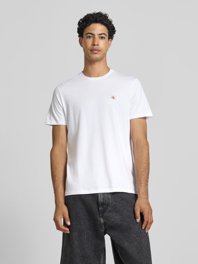 Mężczyznamodel nosi T-Shirt mit Label-Badge od Calvin Klein Jeans, biała bawełna, krój regular fit, okrągły dekolt, długość tyłu 70 cm, Ganzkörperansicht von vorne.