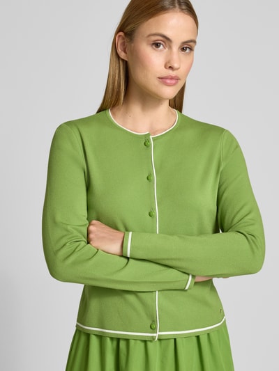Frauenmodel trägt Cardigan aus Viskose-Mix mit Kontrastkante von Marc Cain in Grün mit Rundhalsausschnitt, Gerader-Schnitt, Knopfleiste, Damen, Rückenlänge 51 cm, Ärmellänge 59 cm, Ganzkörperansicht von vorne.