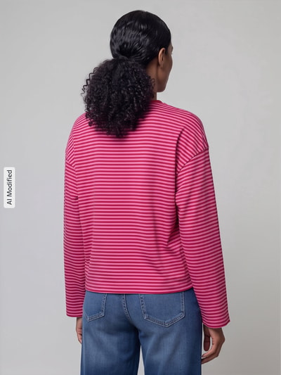 Frauenmodel trägt Relaxed Fit Langarmshirt aus reiner Baumwolle Modell 'FREJA' von ONLY in Pink mit roten Streifen, Damen Langarmshirt von ONLY, Ganzkörperansicht Rückansicht, KI-modifiziertes Bild.