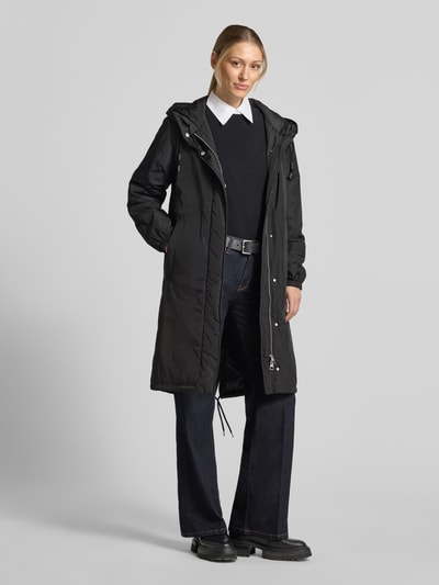 Modelka nosi czarną parkę Regular Fit Parka mit Kapuzenkragen von Marc O'Polo na białej koszuli, ciemnych dżinsach, czarne buty, Ganzkörperansicht von vorne.