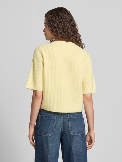 Frauenmodel trägt Boxy Fit Strickjacke aus Rippstrick Modell 'SILLY' von PIECES in Melange-Optik, kurzarm, Material-Mix, Rückansicht.