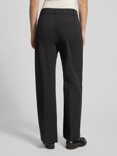 Kobiece model prezentuje spodnie materiałowe 'Stoffhose mit Gesäßtasche' od comma, mieszanka wiskozy z dodatkiem streczu, luźny krój, zakładki w pasie, wpuszczane kieszenie, kieszeń z tyłu, szerokość w rozmiarze 36: 40 cm, długość wewnętrzna nogawki w rozmiarze 36: 77 cm, widok całej sylwetki od tyłu.