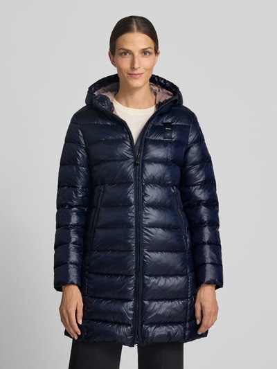 Vrouwenmodel draagt lange jas in Stiksels, regular fit, Capuchon met tunnelkoord, Steekzakken met ritssluiting, Model 'Adelaide' van Blauer USA, Ruglengte maat S 85 cm, Schouderbreedte 40 cm, Borstwijdte 48 cm, Mouwlengte 62 cm, Logo-design, Ganzlichaamsvooraanzicht