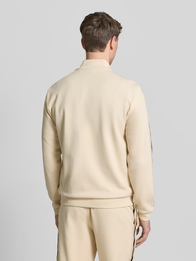 Männermodel trägt Sweatjacke mit Stehkragen und Zweiwege-Reißverschluss von EA7 Emporio Armani, Herren, Regular Fit, Rückenlänge 68 cm, Ärmellänge 67 cm, Eingrifftaschen, Label-Detail, beige Farbe, glatte Struktur, Ganzkörperansicht Rückansicht.