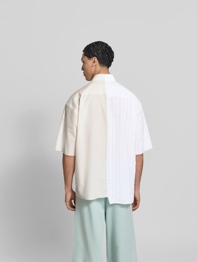 Männermodel trägt Regular Fit Freizeithemd aus Baumwolle von MM6 Maison Margiela, Asymmetrischer-Look, Kent- und Button-Down-Kragen, Halbarm, Rückenlänge 79 cm, Schulterbreite 48 cm, Ärmellänge 30 cm, cremeweiß mit weißem Einsatz, Ganzkörperansicht Rückansicht.