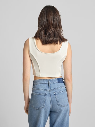 Kobiece model prezentuje crop top z okrągłym dekoltem model 'AGAPA' od Drykorn, mieszanka materiałów z dodatkiem streczu, krój krótki, długość tyłu w rozmiarze S: 22 cm, jasny kolor, gładka faktura, widok całej sylwetki od tyłu.