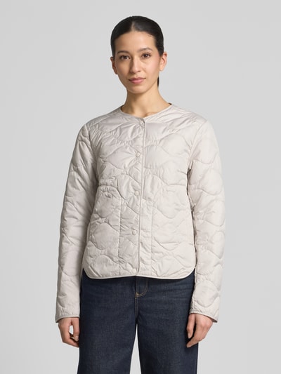 Vrouwenmodel draagt Steppjacke met Rundhalsausschnitt van camel active in licht beige met doorgestikte naden, rechte fit, geheel frontaal zicht, context: dames steppjacke, ronde hals, drukknoopsluiting, ruglengte 60 cm, schouderbreedte 43 cm, borstwijdte 53 cm, mouwlengte 64 cm.