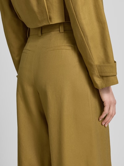 Frauenmodel trägt Bermudas aus Leinen-Baumwoll-Mix mit Gürtel von Style Icon Collection in Oliv, strukturierte Oberfläche, Detailaufnahme Rückenansicht. Relaxed Fit, gelegte Falten, Bundweite 37 cm, Innenbeinlänge 45 cm.