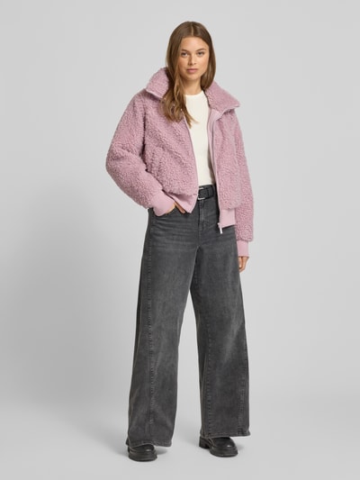 Frauenmodel trägt Teddyjacke mit Stehkragen und Reißverschluss von Mazine in Rosa, weiches Teddyfell, Regular Fit, Ganzkörperansicht von vorne.