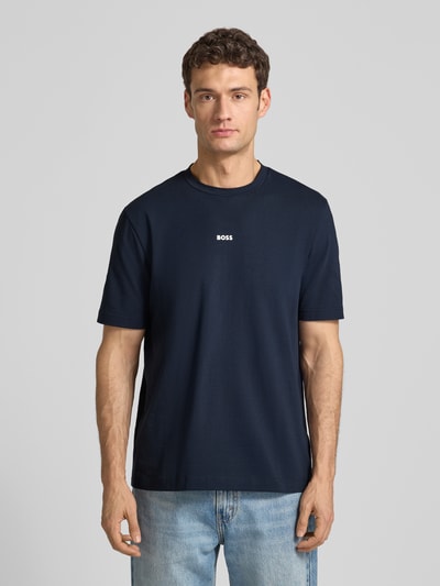 Männermodel trägt T-Shirt mit Label-Print von BOSS, dunkelblau, Baumwoll-Elasthan-Mix, Regular-Fit, Rundhalsausschnitt, Ganzkörperansicht von vorne. Rückenlänge bei Größe M: 70 cm.