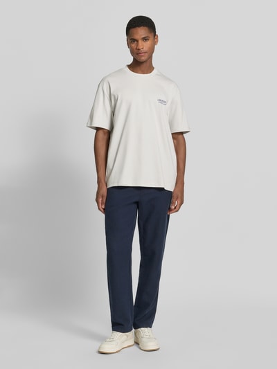 Männermodel trägt Oversized T-Shirt mit Label-Print von Lindbergh in Off-White, Reine Baumwolle, Rundhalsausschnitt, Rückenlänge 70 cm, Ganzkörperansicht von vorne.