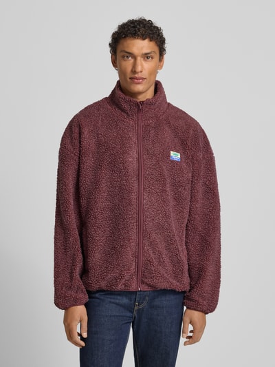 Männermodel trägt Fleecejacke mit Stehkragen Modell 'HOKTOWN' von American Vintage, Relaxed-Fit, Label-Detail, Ganzkörperansicht von vorne.