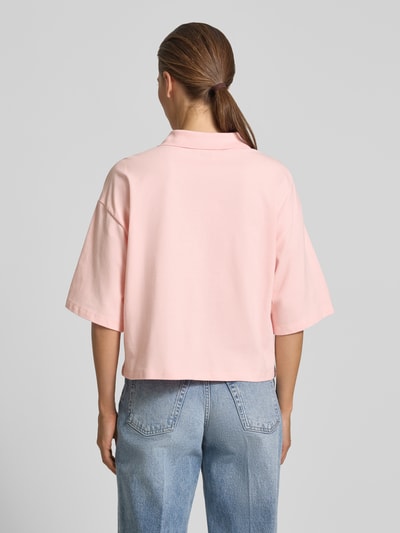 Frauenmodel trägt Cropped Poloshirt mit Ziersteinbesatz von Smith and Soul in Hellrosa aus elastischem Baumwoll-Mix, Rückenlänge 55 cm, Ganzkörperansicht Rückansicht.