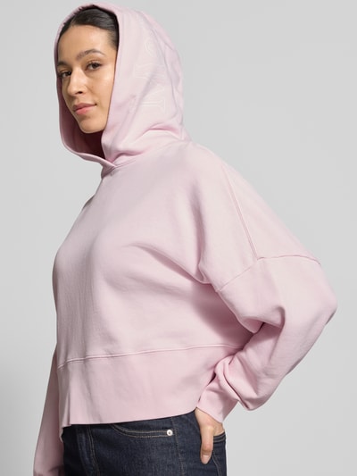 Vrouwenmodel draagt Relaxed Fit Hoodie uit zuiver katoen van Marc O'Polo in effen kleuren, sweatstof, labelprint, lange mouw, capuchon. Zijaanzicht bovenlichaam.