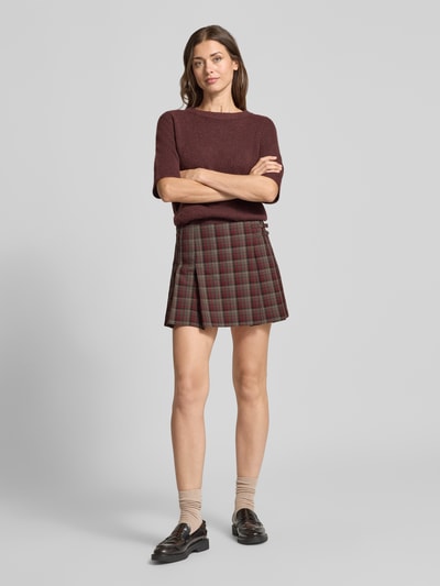 Frauenmodel trägt Minirock mit Falten Modell 'PUNK' von MANGO im Allover-Karo-Look, A-Linie, Material-Mix, Ganzkörperansicht von vorne.